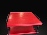 an image of a red table with wheels on a black background