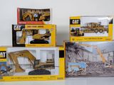 three boxed boxes of construction toys including a cat excavator, a bulldozer, and a bulldozer