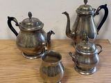 three silver teapots sitting on a wooden table