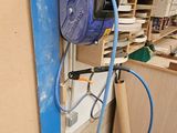 un tuyau bleu fixé au mur, à côté d'un tas de bois