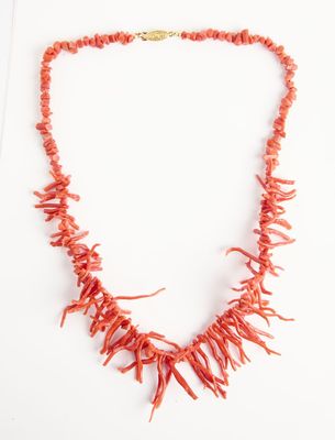 collier composé de perles de corail rouge avec un fermoir en or sur fond blanc