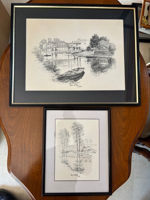 deux photos encadrées représentant des bateaux, posées sur une table à côté d'une chaise