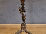 une statue antique en bronze représentant une femme tenant un vase, posée sur un socle