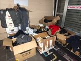 de nombreux cartons de vêtements posés par terre devant une porte