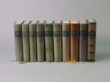 several books are stacked on top of each other on a white surface
