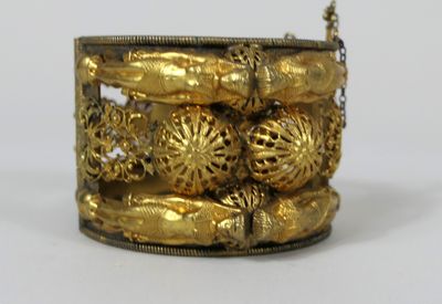 Gros bracelet rigide en métal doré repercé à décor de caboch…