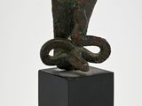 sculpture of a snake sitting on a black base on a white background