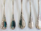 five silver spoons and a fork on a white table