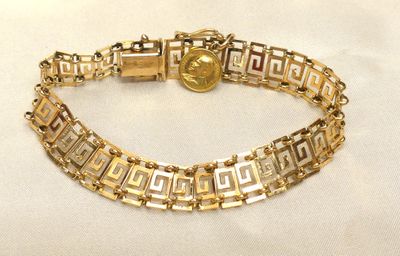 Gros plan sur un bracelet en or orné d'une pièce de monnaie
