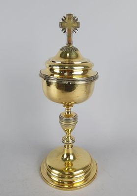 une urne plaquée or surmontée d'une croix