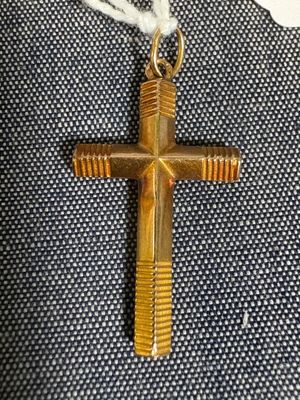 une croix en or suspendue à un cordon blanc sur un tissu bleu