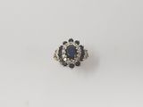 a close up of a diamond and sapphire ring on a white surface
