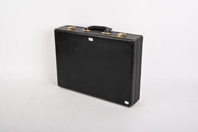 une valise noire posée sur une surface blanche