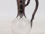 a glass pitcher with a metal handle on a white surface