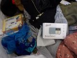 a teddy bear sitting on a bed next to a box of clothes
