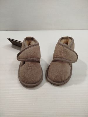 une paire de chaussures de bébé marron avec un stylo sur un fond blanc