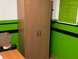 a wooden cabinet in the corner of a room with a green wall