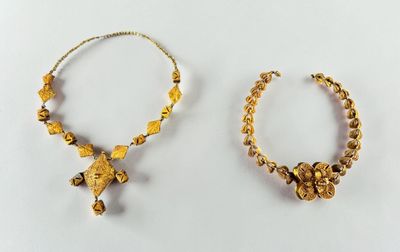 two pieces of gold jewelry on a white surface