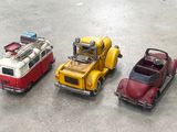 three toy cars sitting next to each other on the ground