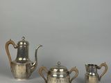 three pieces of silver tea and coffee set on a table