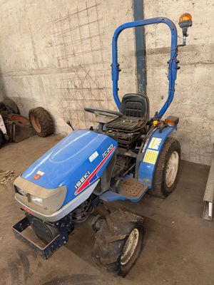 un tracteur bleu garé dans un garage, près d'un mur