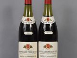 two bottles of red wine sit on a table next to each other