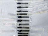 Plusieurs stylos sont alignés en rangée sur une surface blanche