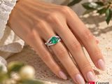 the woman is wearing a ring with a green stone on it