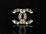 a close up of a chanel broocher on a black surface