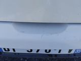 the front bumper of a white car with a blue and white number plate