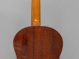 an old wooden guitar hanging on a wall with a gray background