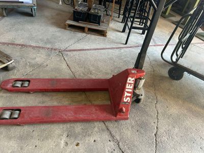 un chariot élévateur rouge posé au sol dans un entrepôt