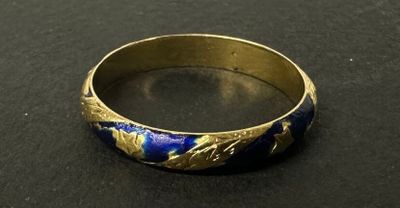 un gros plan d'une bague dorée et bleue posée sur une surface noire