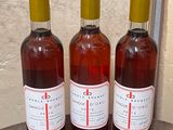 three bottles of wine sitting on top of a wooden barrel