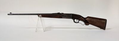 un gros plan d'un fusil posé sur un socle transparent, sur fond blanc