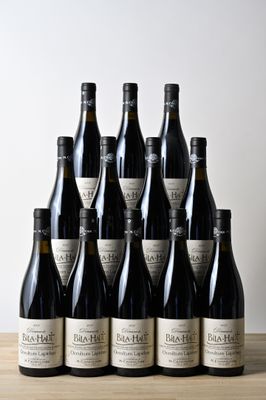 six bouteilles de vin sont posées sur une table en bois devant un mur blanc