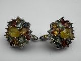 two pairs of earrings with multi colored stones on a white surface
