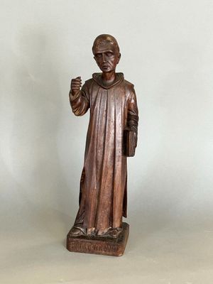 wooden statue of a monk holding a book and a candle