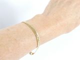 someone is wearing a gold bracelet with a chain on their arm
