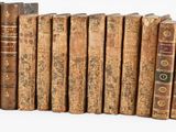 several old books are lined up in a row on a white surface