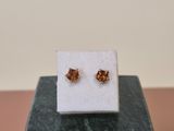 a pair of earrings sitting on top of a marble block