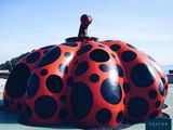 a large red and black polka dot pumpkin sculpture on the ground