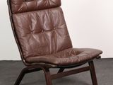 the chair is made of brown leather and has a wooden frame