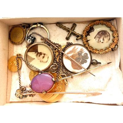 une boîte contenant divers objets, notamment un collier, des broches et d'autres articles