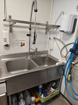 a stainless steel sink and a washing machine in a small room