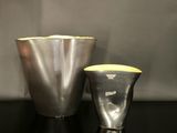 un vase en argent et un vase en argent posés sur une table noire