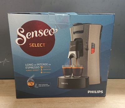 La boîte de la cafetière est ouverte sur la table.