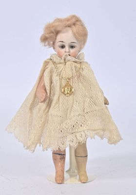 an antique doll with blonde hair wearing a cape and boots