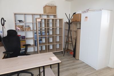 a desk with a chair and a refrigerator in a room
