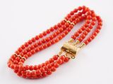 a close up of a red beaded necklace with a gold clasp